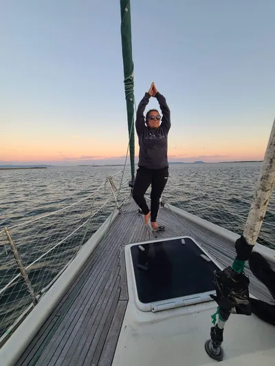 Lori in a seated forward fold on the bow of a boat, Lake Superior behind her