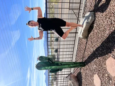 Lori in cactus pose on a rocky outcrop, arms open wide